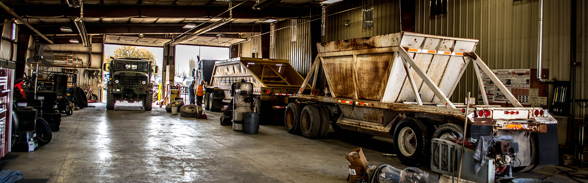 Inside the JB Tire shop with commercial trucks and dump trailers in the service bay